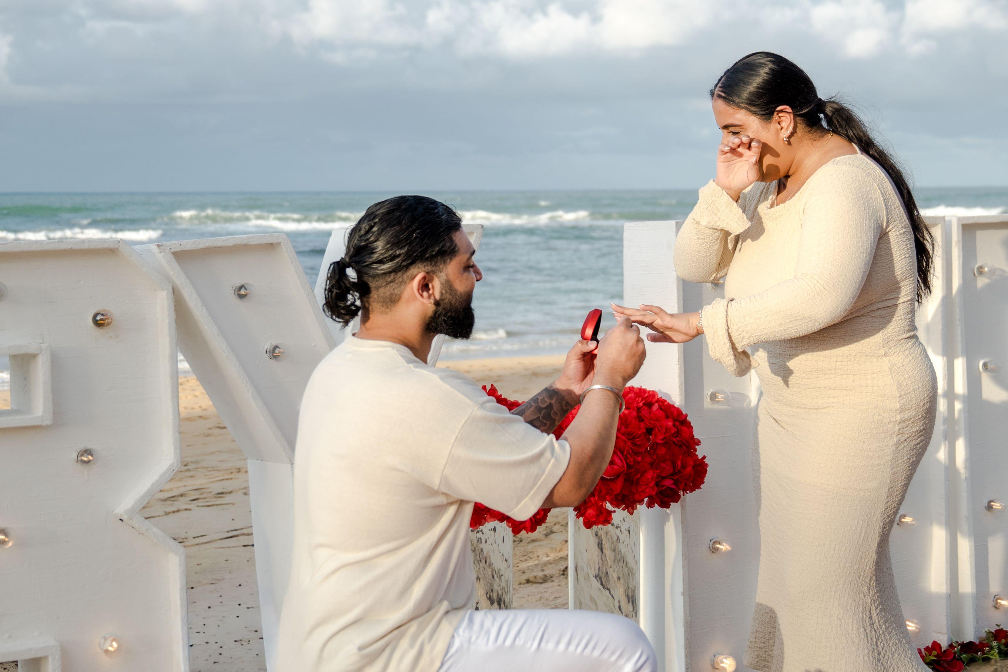 Proposition de fiançailles romantique à Punta Cana avec bougies, roses et dîner élégant face à la mer au coucher du soleil